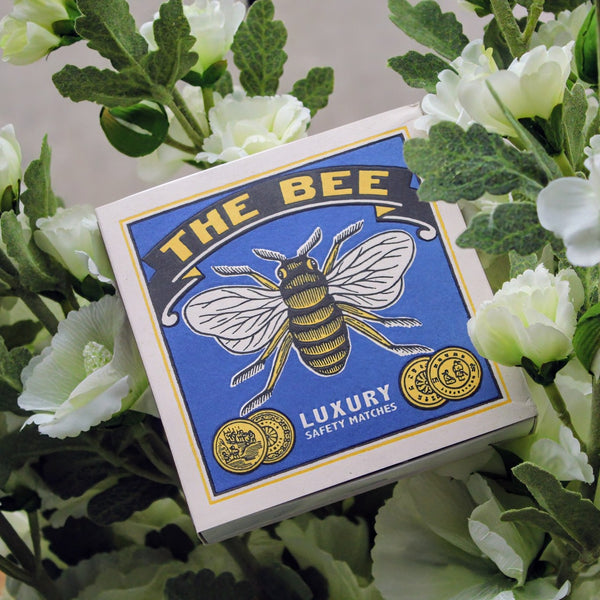 Letterpress-printed matchbox with a classic bee illustration, paired with the phrase 'The Bee' for a charming and easy way to light candles or fires.