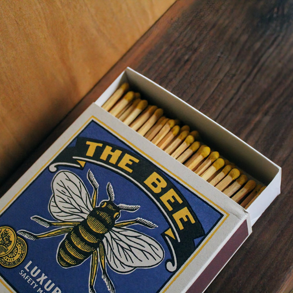 Letterpress-printed matchbox with a classic bee illustration, paired with the phrase 'The Bee' for a charming and easy way to light candles or fires.