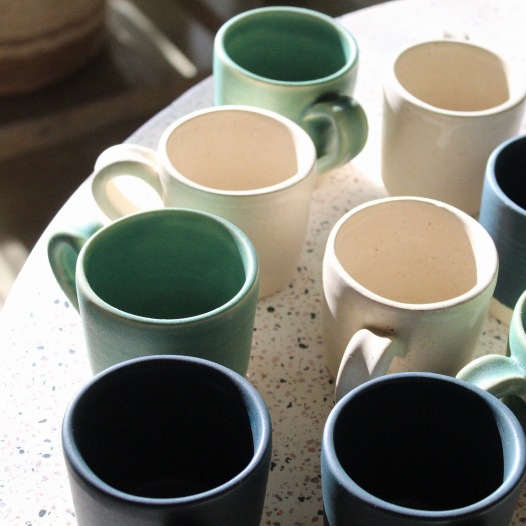 A grouping of handmade mini mugs in assorted colors 