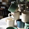 A stack of handmade mini mugs in assorted colors - natural sunlight 