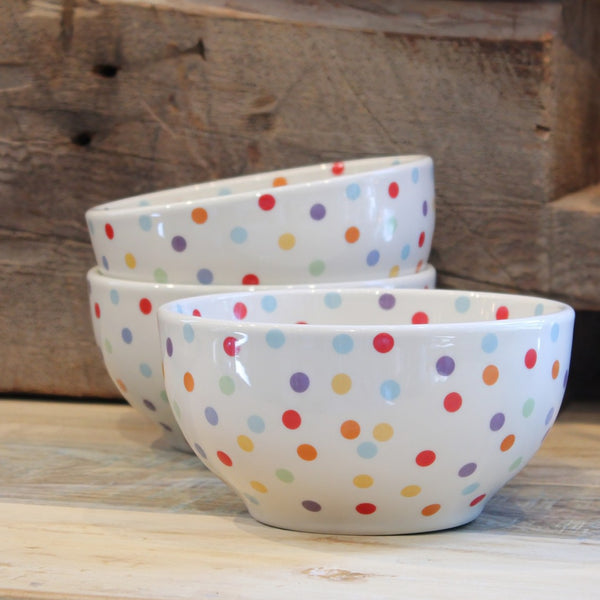 Ceramic bowls with colorful polka dots on a wooden surface.