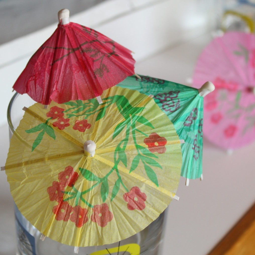 close up view of the colorfully decorated paper drink umbrellas in a glass