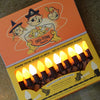 A box of Tru-Tone Halloween-style lights with illustrated pirate and witch graphics on the lid, shown open to reveal multiple yellow orange and white  glowing bulbs in a windowed lower section.