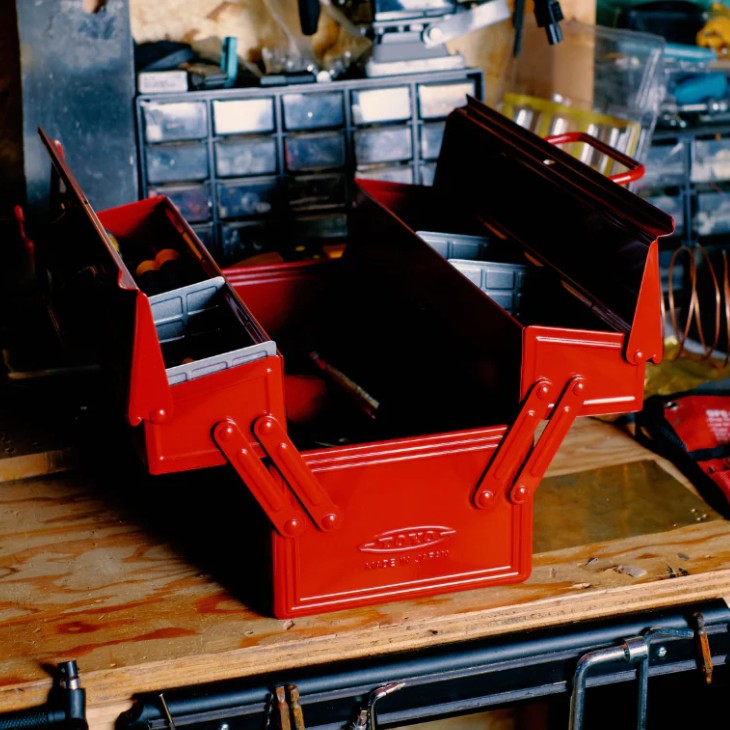 Red toolbox on a wooden surface with a workshop background