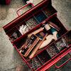 Open red toolbox with various tools and hardware on a concrete floor.