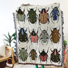 A fringed throw blanket with colorful beetles